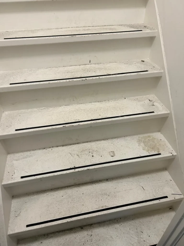 Trappenhuis van een VvE voor de schoonmaak, met vuil en vlekken op de treden