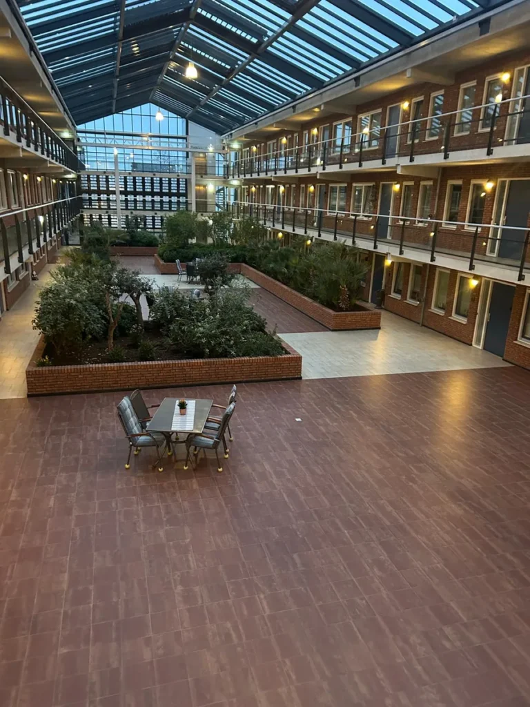 Overdekt atrium van een appartementencomplex met glazen kap en beplanting