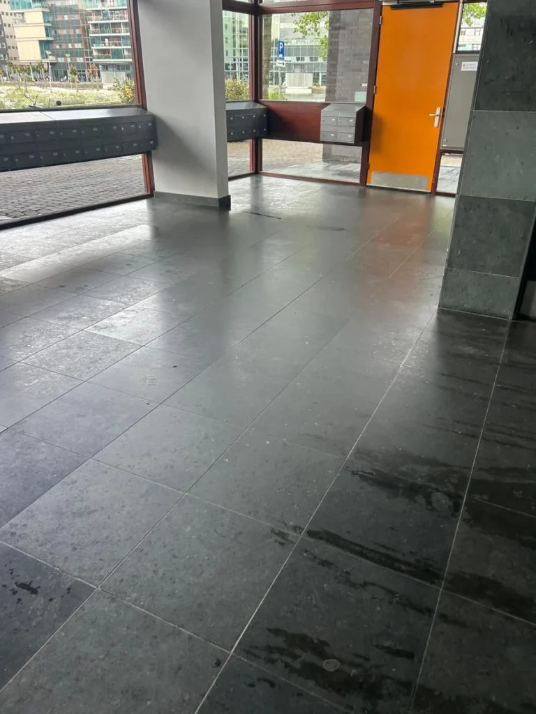 Entree van een VvE met schoongemaakte natuursteenvloer en brievenbussen