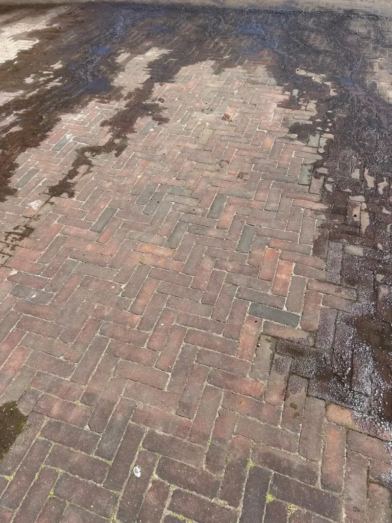 Bestrating tijdens het schoonspuiten, het schone deel steekt licht af tegen het vuile deel